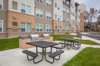 A black table with four benches is in front of a building.